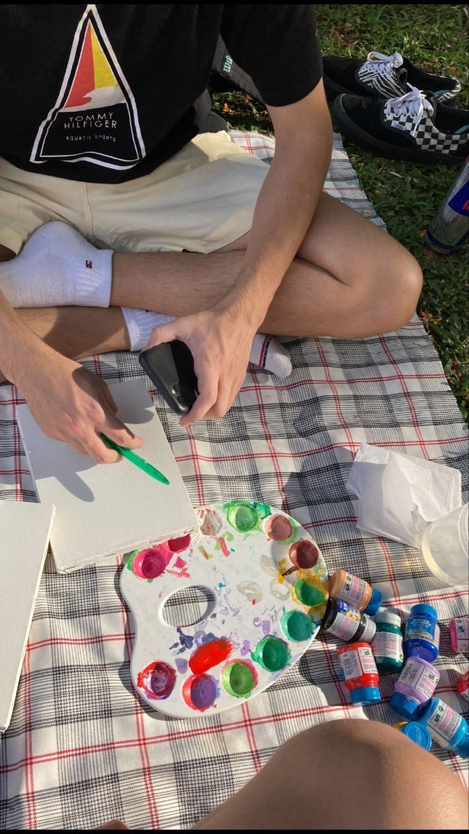 a man sitting on top of a blanket painting