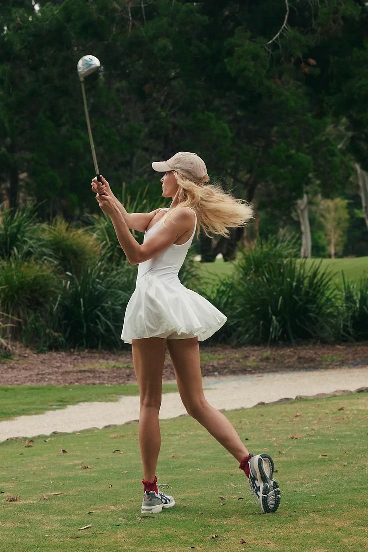 a woman in a short white dress hitting a ball with a tennis racquet