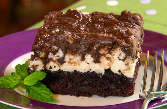 a piece of chocolate cake with white frosting and oreo cookies on top sitting on a plate