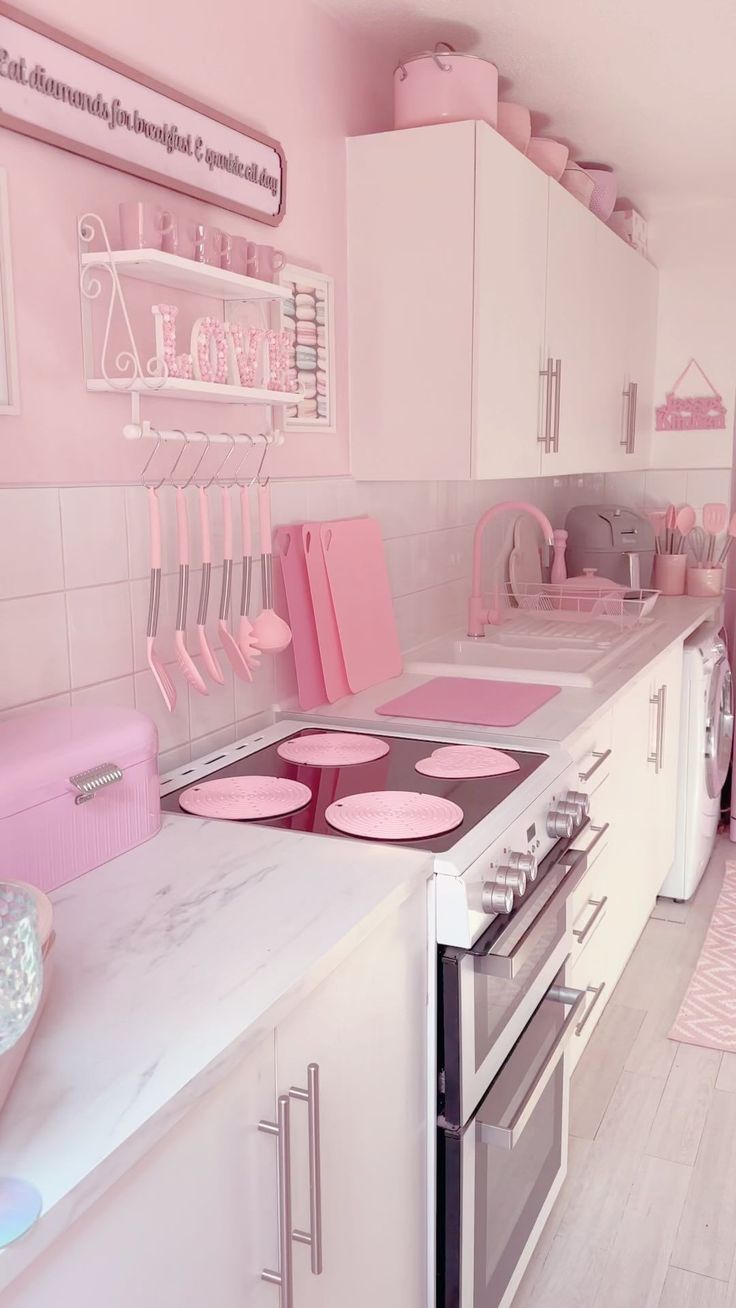 a pink and white kitchen with lots of counter space