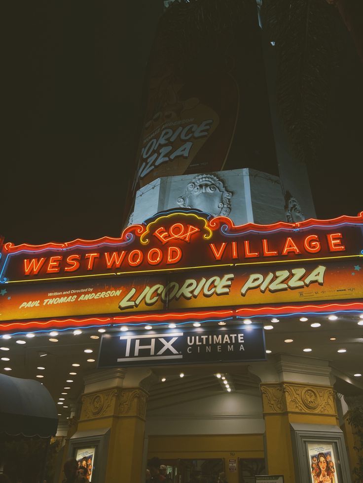 the marquee for westwood village is lit up at night with neon lights