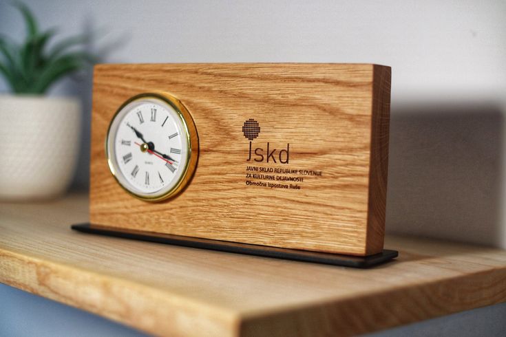 a wooden clock sitting on top of a table next to a potted green plant