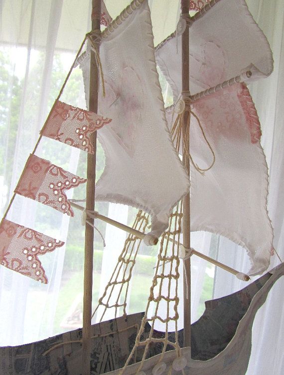 a sailboat made out of fabric and rope on display in front of a window