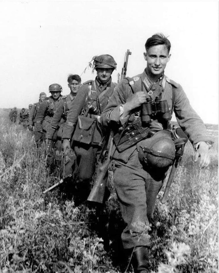 a group of men in uniforms walking through a field