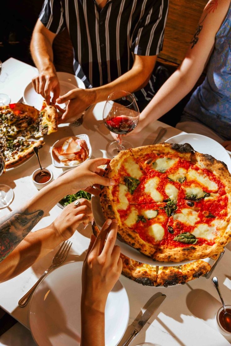 several people sitting at a table eating pizza