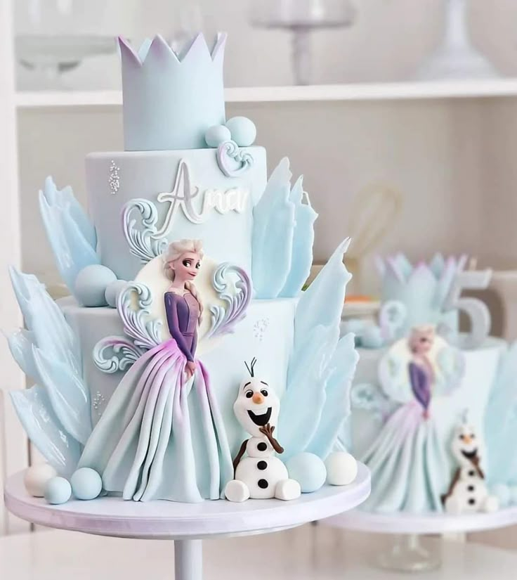 there is a cake decorated with frozen princesses and snowmen on the top tier