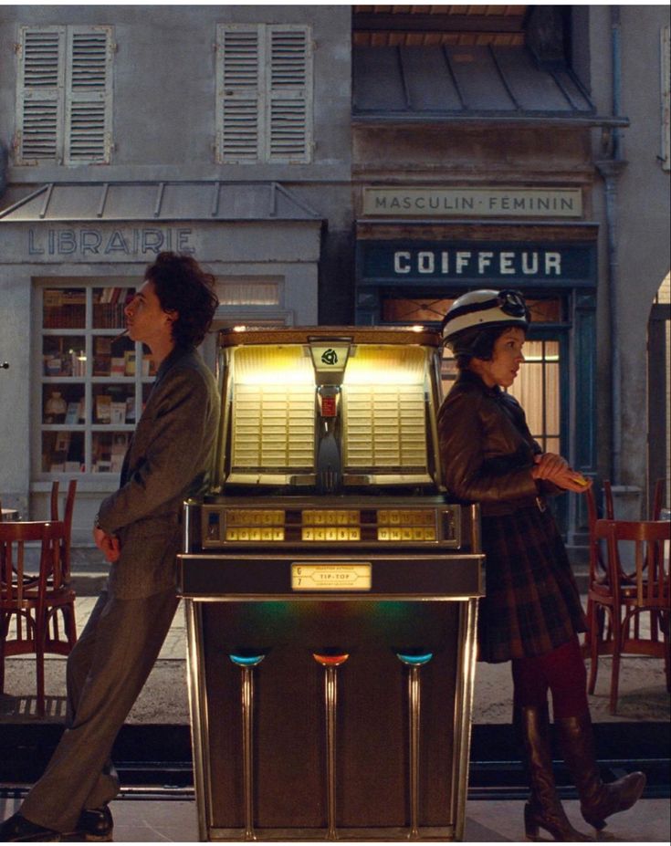 two people walking past a juke machine on the street