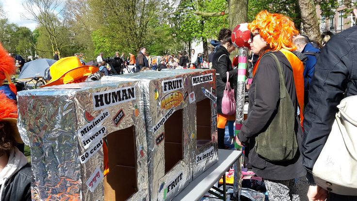 a group of people standing around an ice box with orange hair on it's head