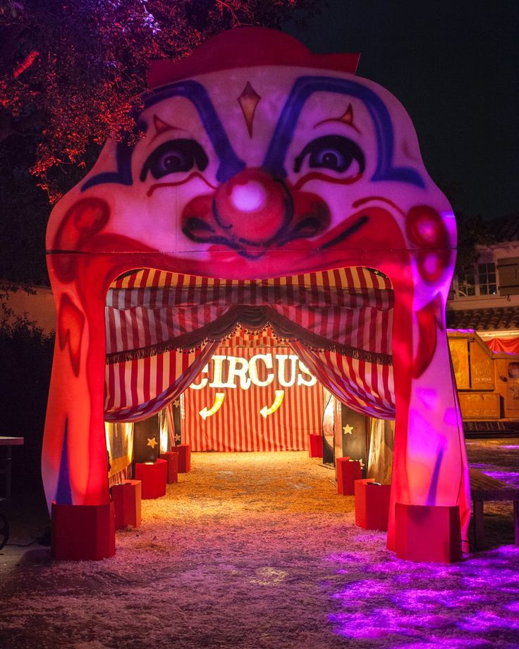 an elaborately decorated circus tent is lit up with purple lights and red curtains for the entrance