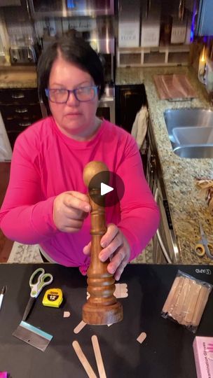 a woman is making something out of wood with scissors and other items on the table