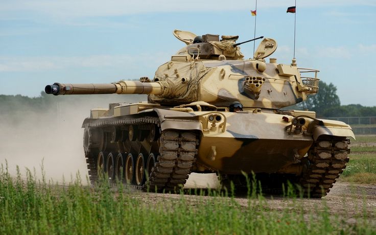 an army tank driving down a dirt road