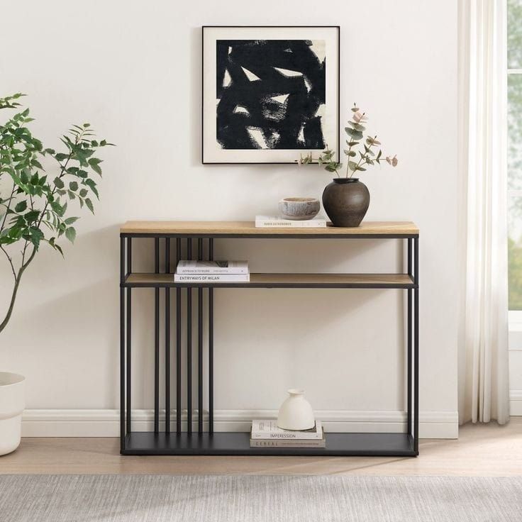 a modern console table with an abstract painting on the wall above it and a potted plant next to it