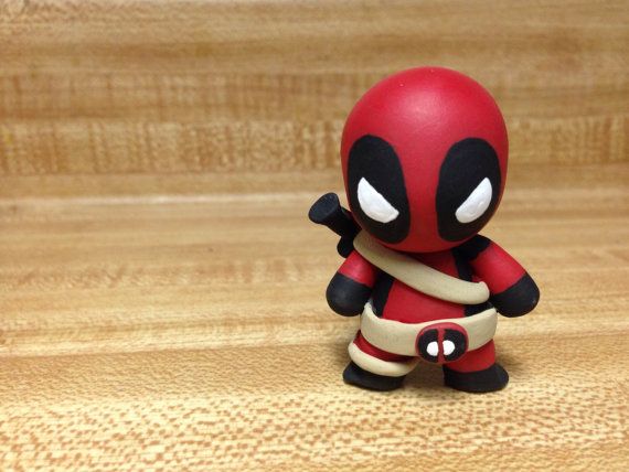 a deadpool figurine sitting on top of a wooden table