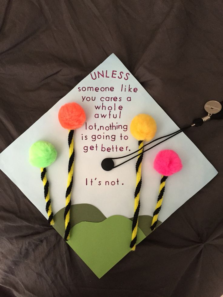 a graduation cap decorated with pom - poms on top of a sheet of paper