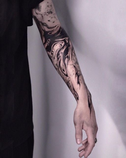 a man's arm is covered in black and grey ink with an abstract design