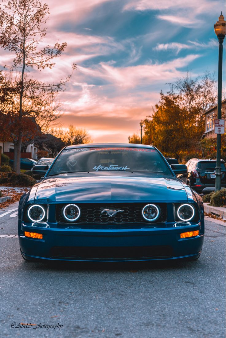 the front end of a blue mustang parked in a parking lot