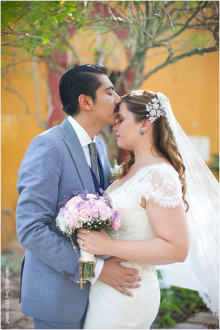 a bride and groom kissing in front of trees