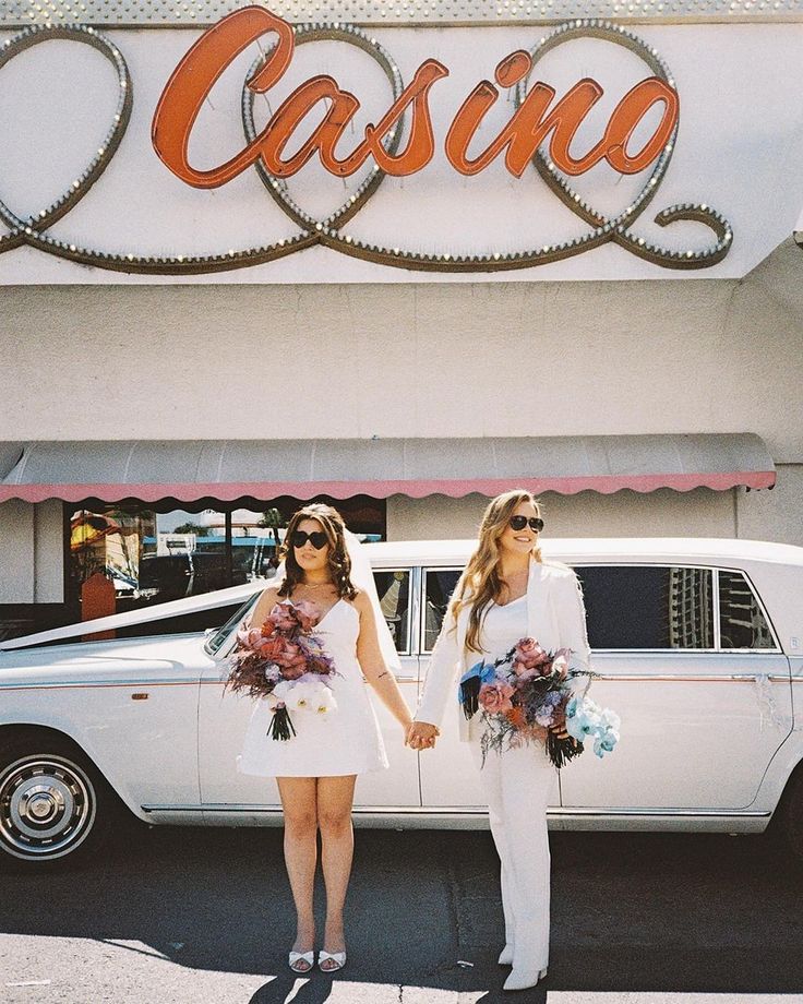 two women standing next to each other in front of a white car with the word casino on it