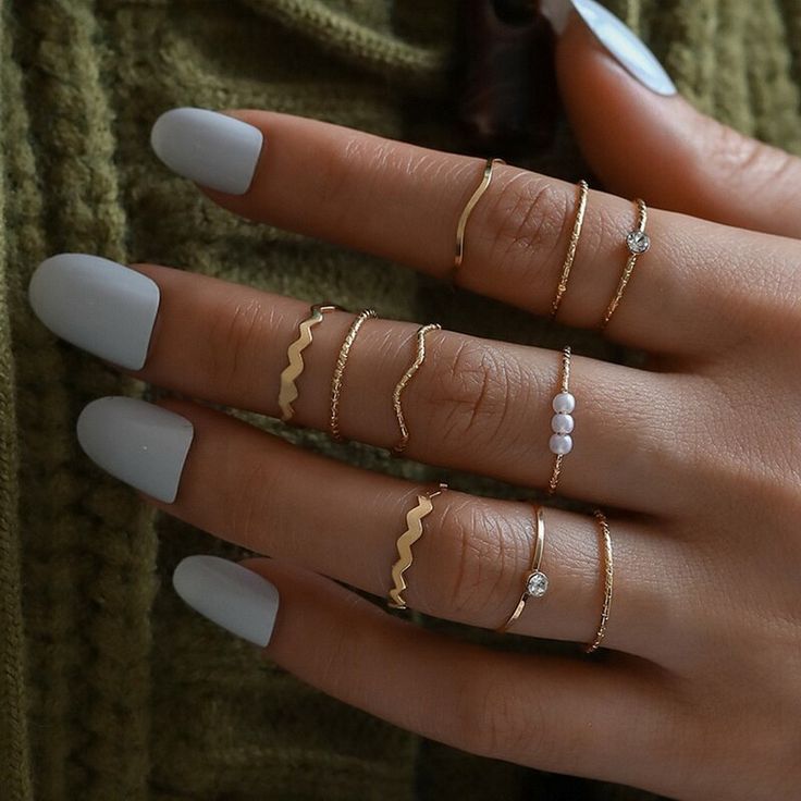 a woman's hand with five different rings on her fingers and one ring in the middle