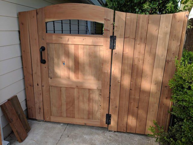 a wooden gate is open on the side of a house