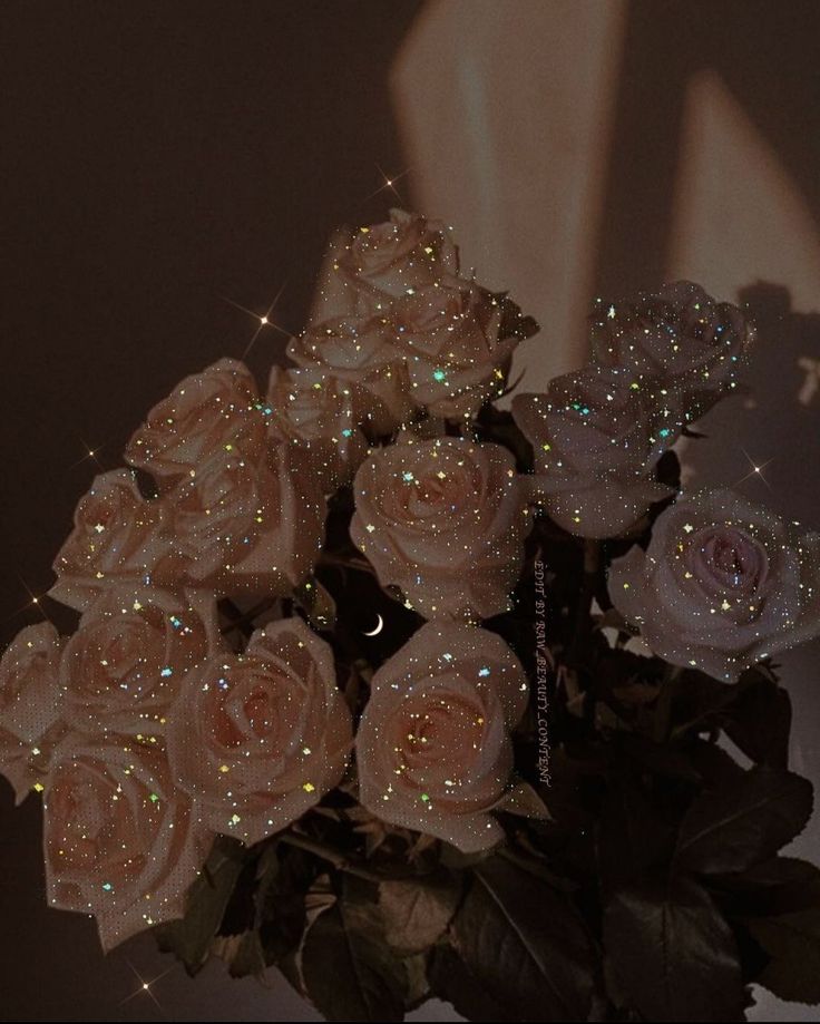 a vase filled with lots of pink roses on top of a table next to a wall