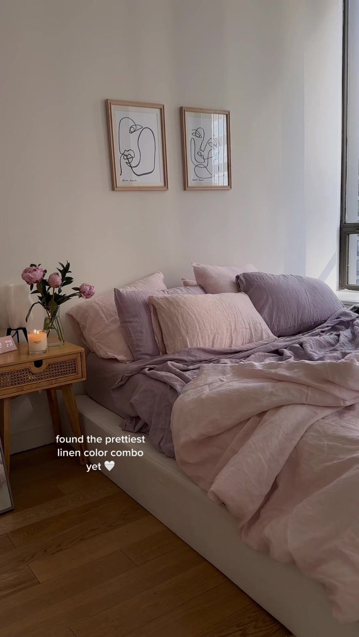 a bed that has some pillows on top of it and two pictures above the bed