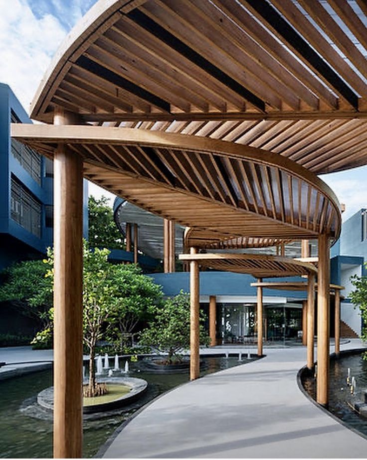 the walkway is lined with wooden benches and water features in the center, surrounded by trees