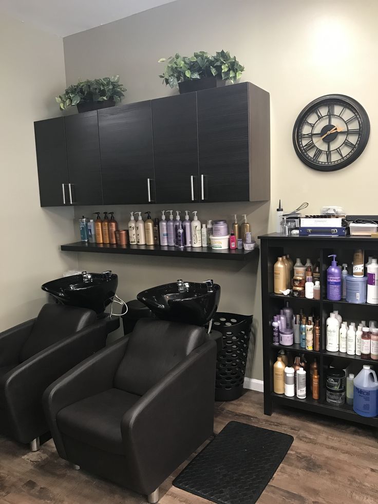 a hair salon with black chairs and shelves filled with bottles, shampoos and other items