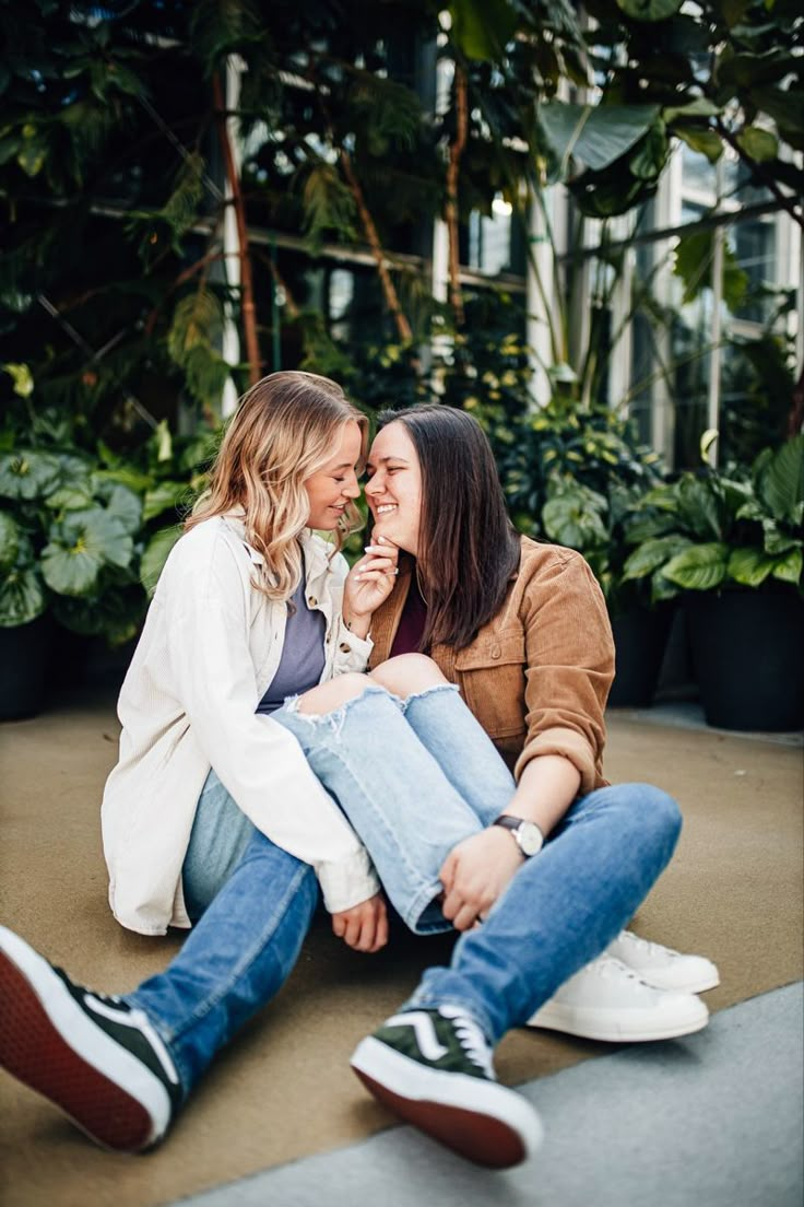 two women are sitting on the ground and one has her mouth open to another woman's face