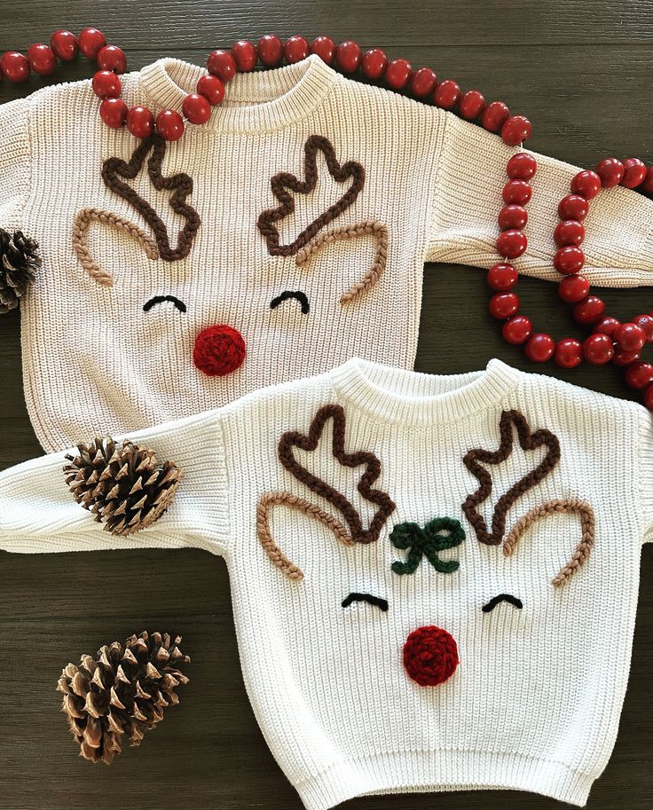 two knitted reindeer sweaters with red beads and pine cones