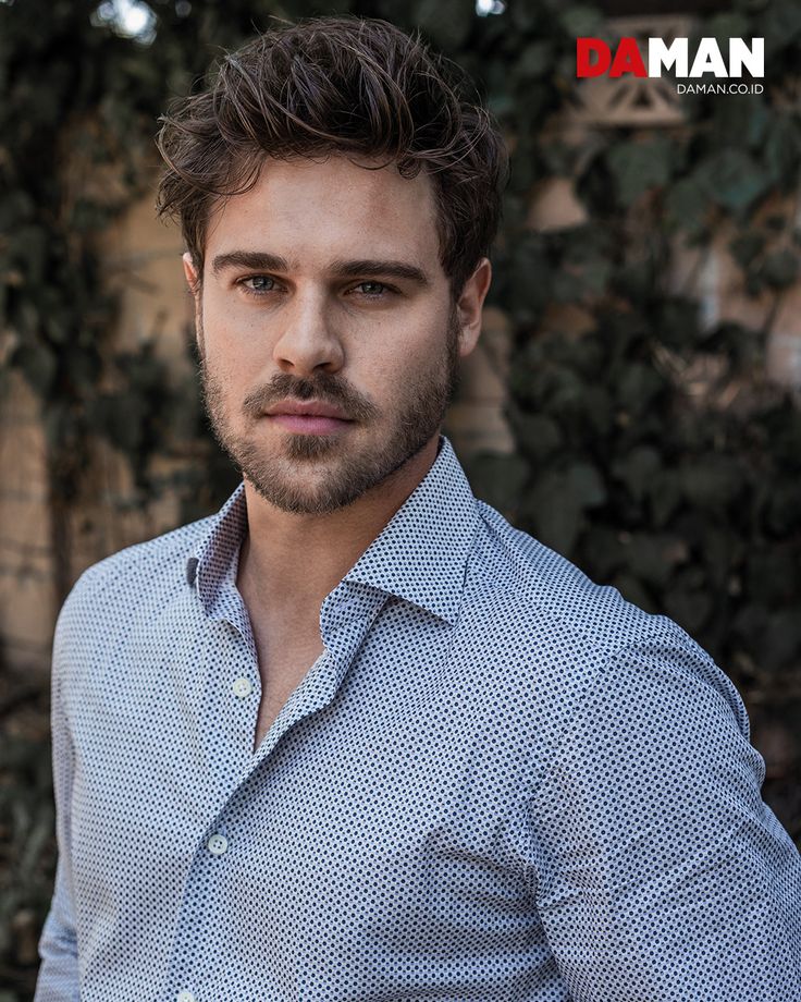 a man in a blue shirt is posing for the camera with his hands on his hips