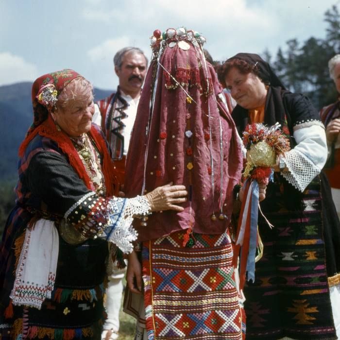 an old photo of some people dressed in traditional clothing and headdress, with one woman holding the other's hand