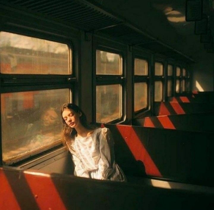 a woman is sitting on a train looking out the window