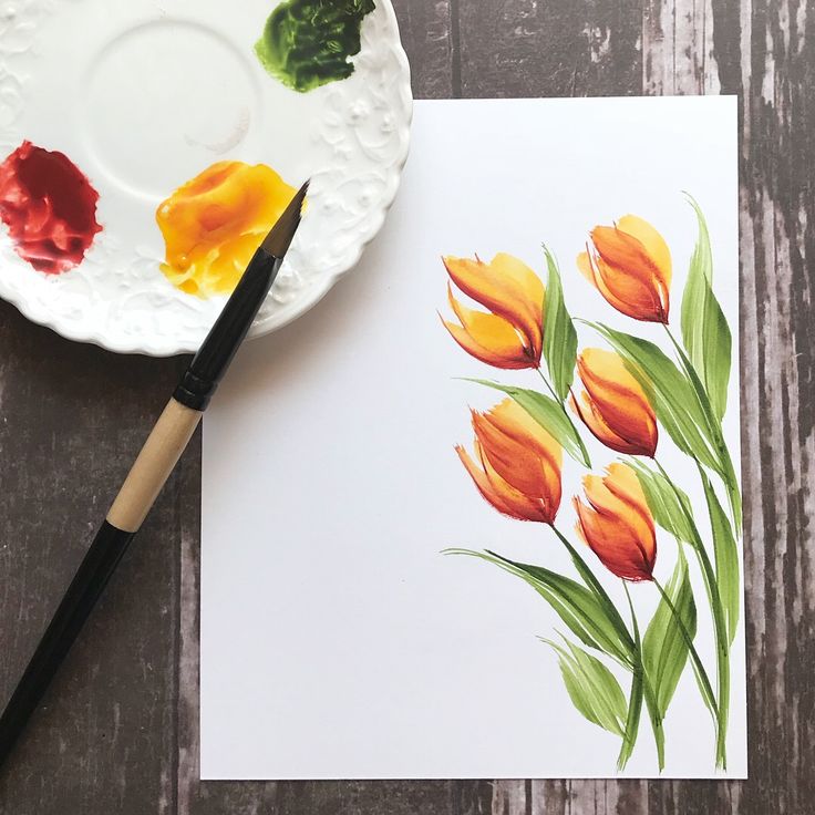 a watercolor painting of orange tulips on a white plate next to a paintbrush