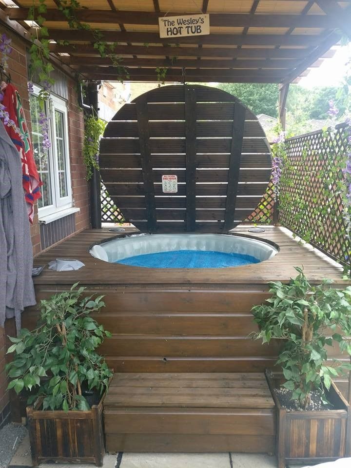 a hot tub sitting on top of a wooden deck next to potted planters