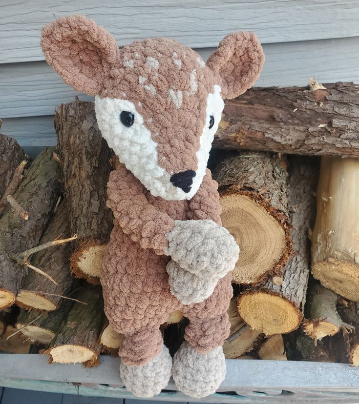 a crocheted stuffed animal sitting on top of a pile of logs