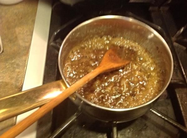 a wooden spoon in a pot on top of a stove with food cooking inside it