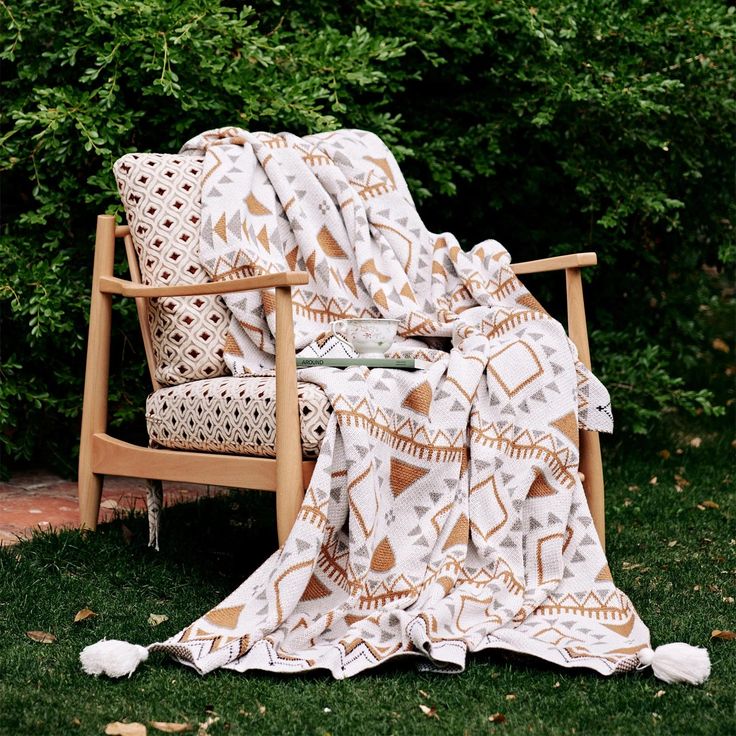 a chair with a blanket on it sitting in the grass