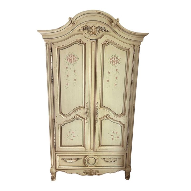 an antique white armoire with floral designs