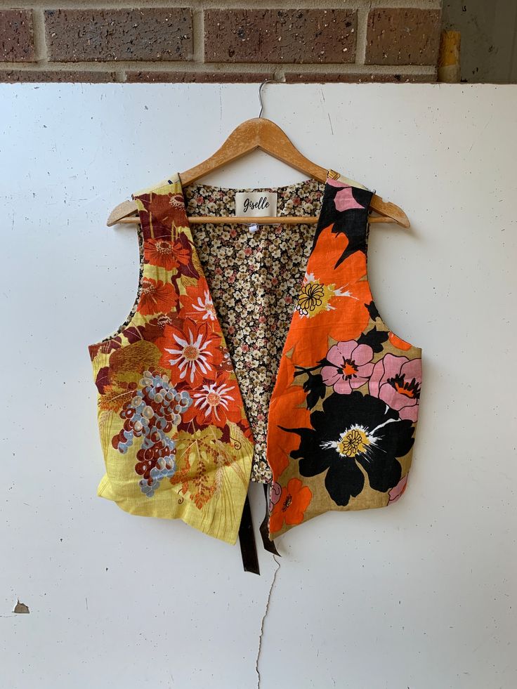 an orange and black floral vest hanging on a wall