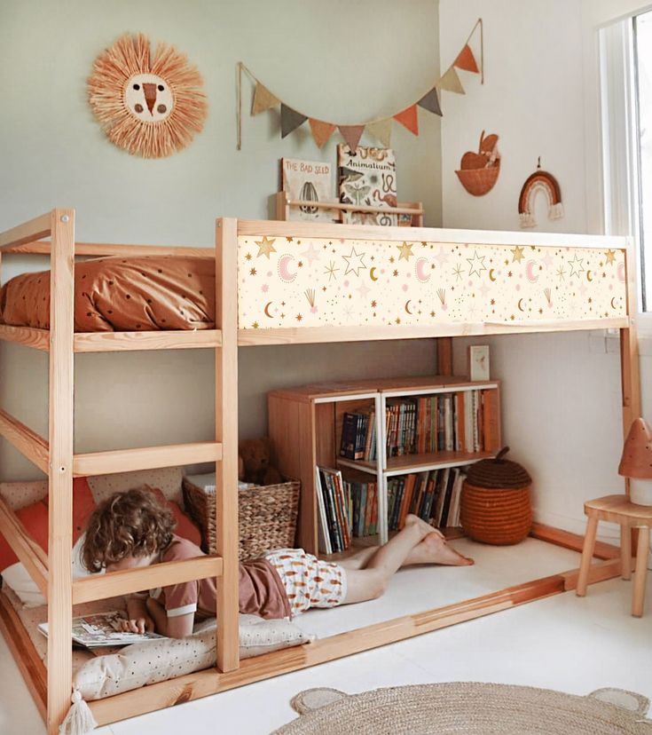 there is a child sitting on the bottom bunk bed in this room with bookshelves