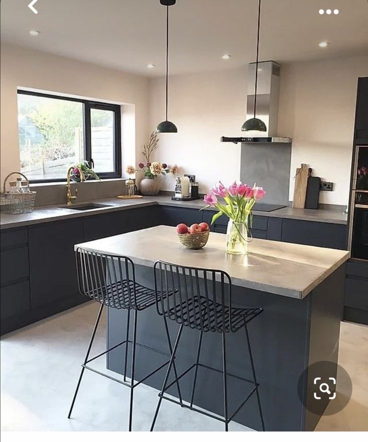 a kitchen with two bar stools in front of the counter and an island that has flowers on it