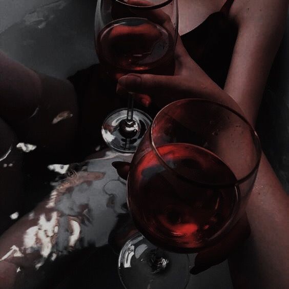 two women are holding wine glasses while sitting on the floor with their feet up in the air