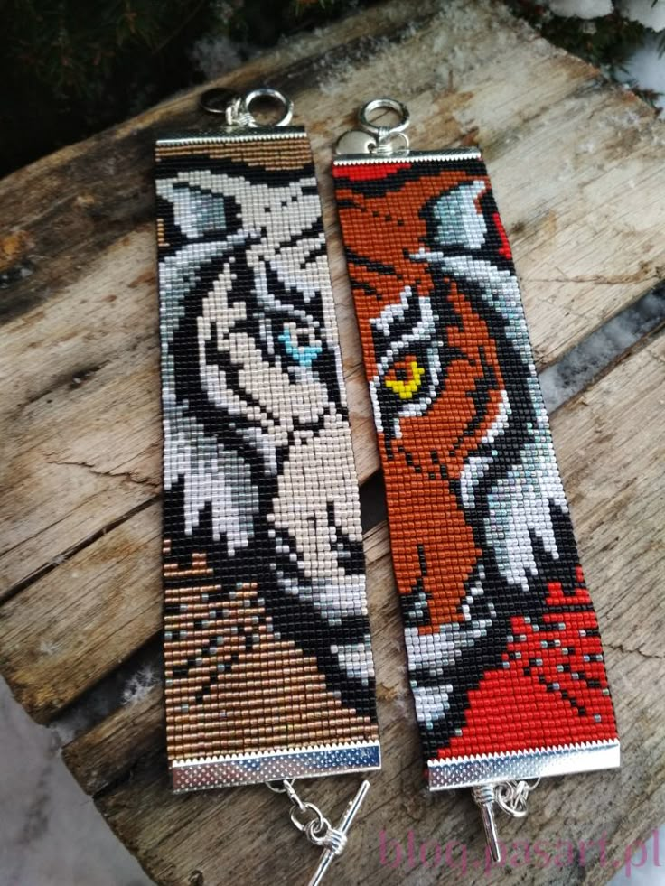 two beaded bracelets with tigers on them sitting on top of a piece of wood