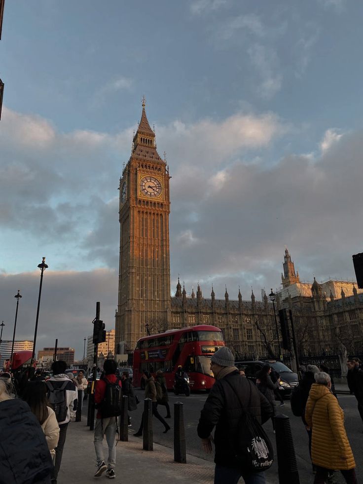 the big ben clock tower towering over the city of london, england as people walk by