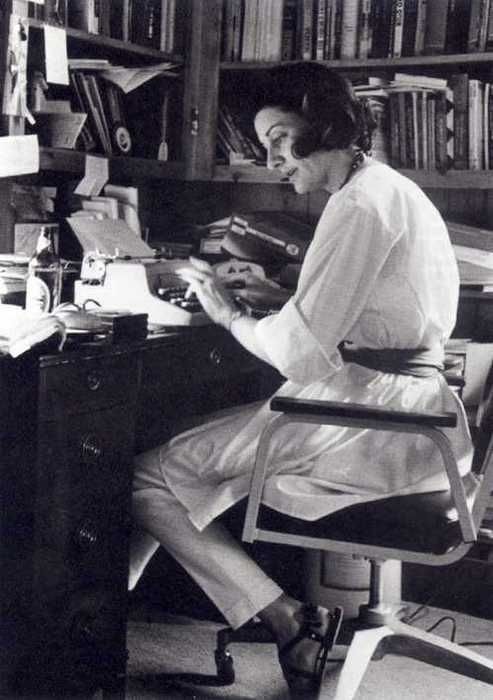 a woman sitting at a desk in front of a book shelf