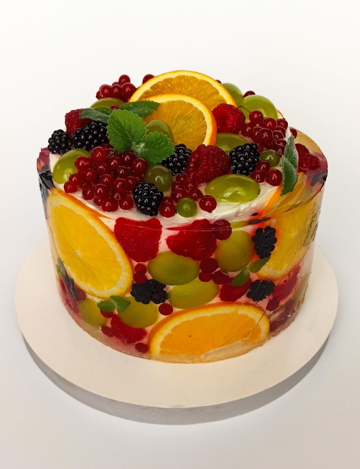 a cake decorated with fruit and berries on a white plate, ready to be eaten