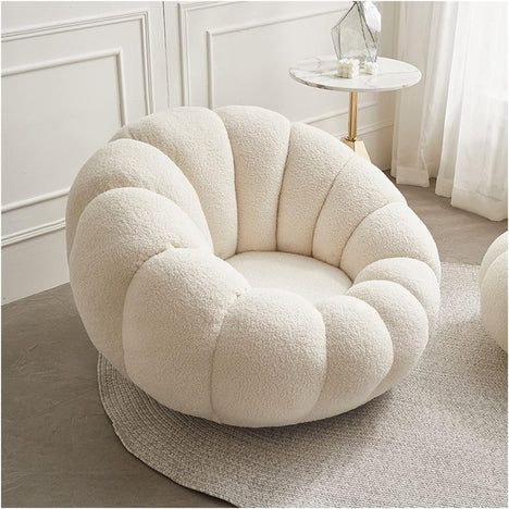 a white chair sitting on top of a rug in a living room next to a table