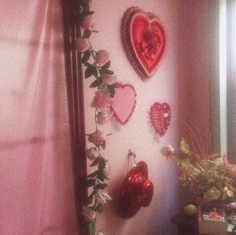 there are many heart shaped decorations hanging on the wall in this room with pink walls