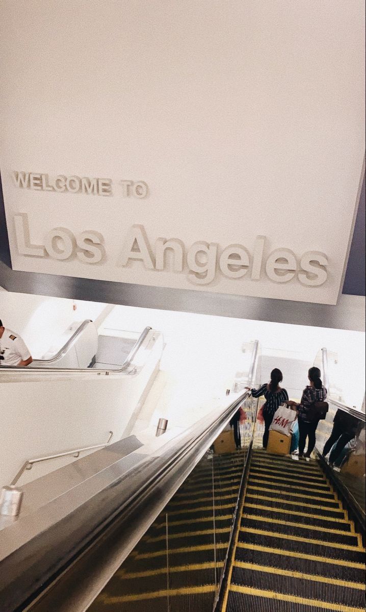 people are riding down an escalator at the los angeles airport